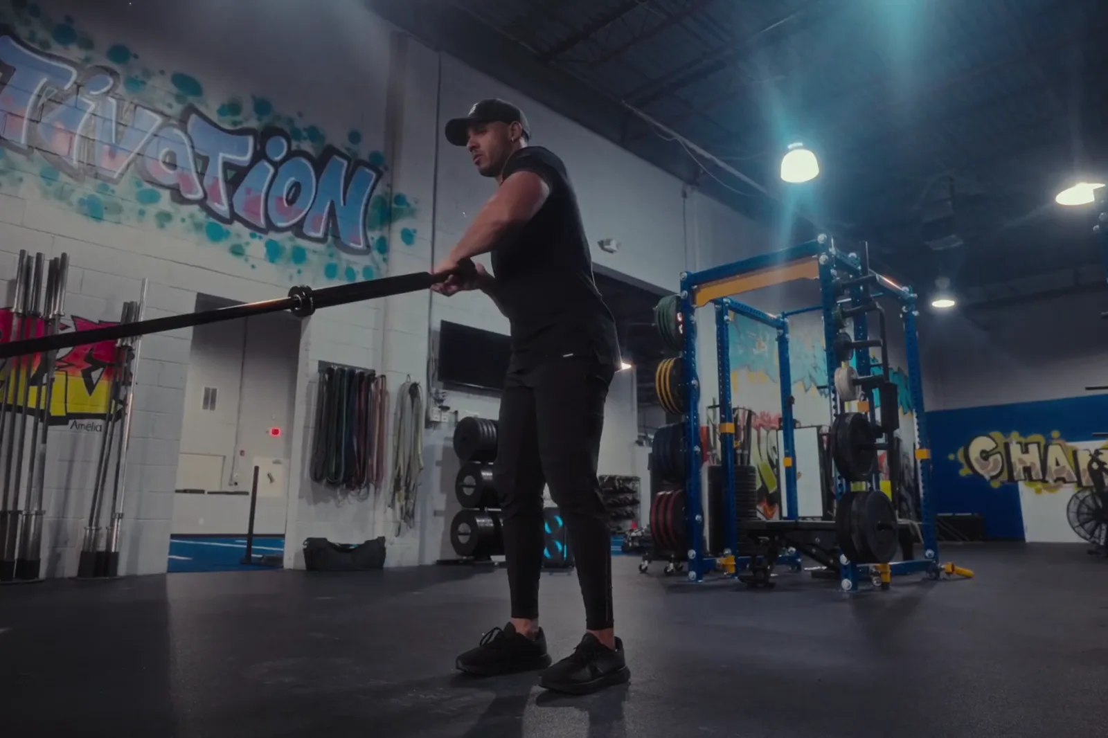 Collis Spann standing with the Spann Bar seated in a landmine, about to drop into a lunge and press, in his gym.
