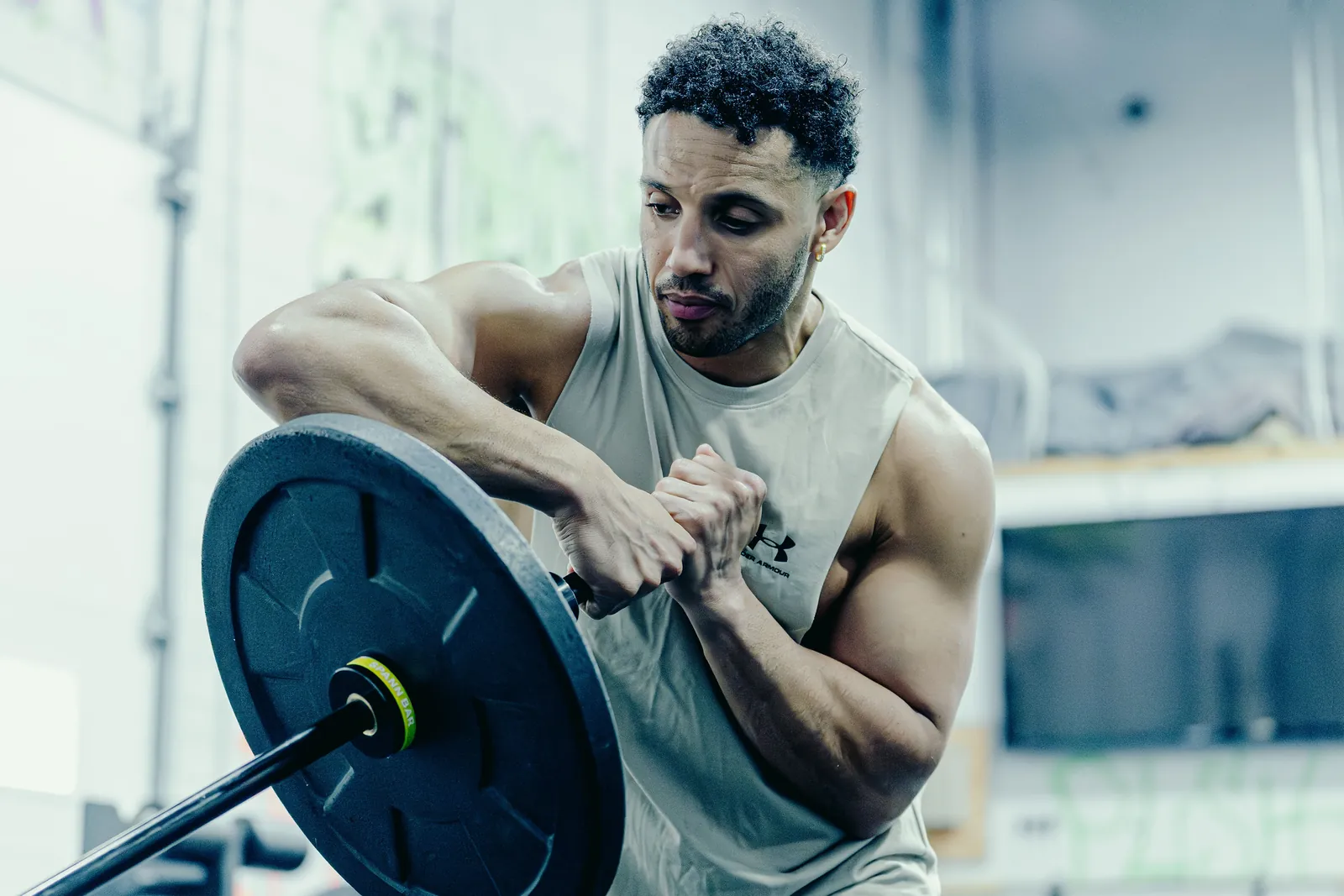 An athlete braced over the loaded Melo Bar at his chest, the yellow collar by the plate.