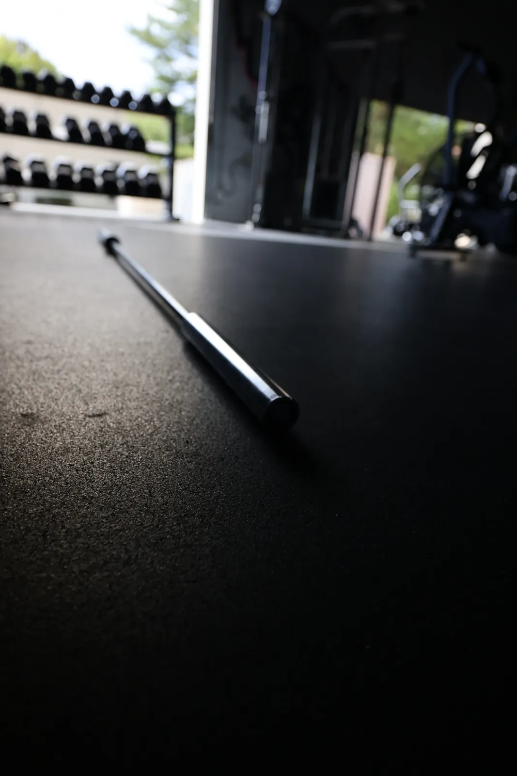 The Spann Bar on the gym floor by the open garage door, a dumbbell rack behind it.