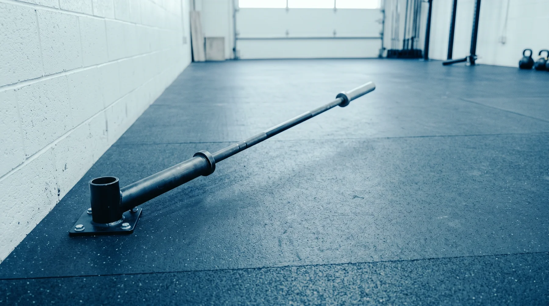 A standard Olympic barbell pushed into a landmine sleeve on a gym floor, the long far end sticking out.