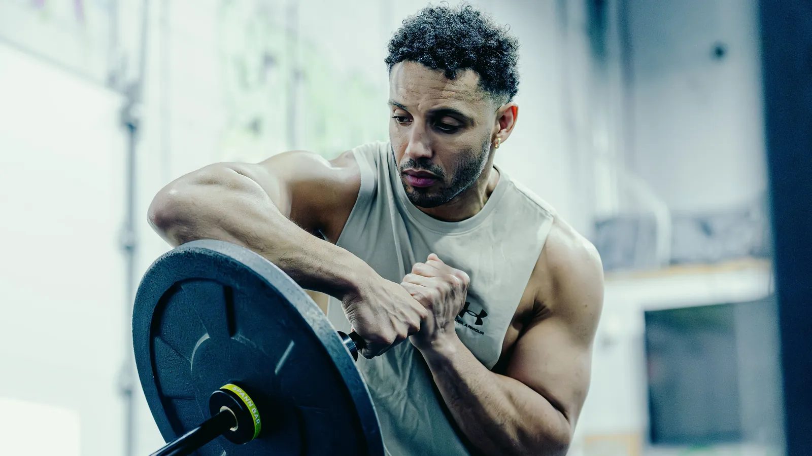 How to squat with a landmine: a lifter holding the loaded end of the Melo Bar at his chest in both hands, the yellow collar sitting behind the plate