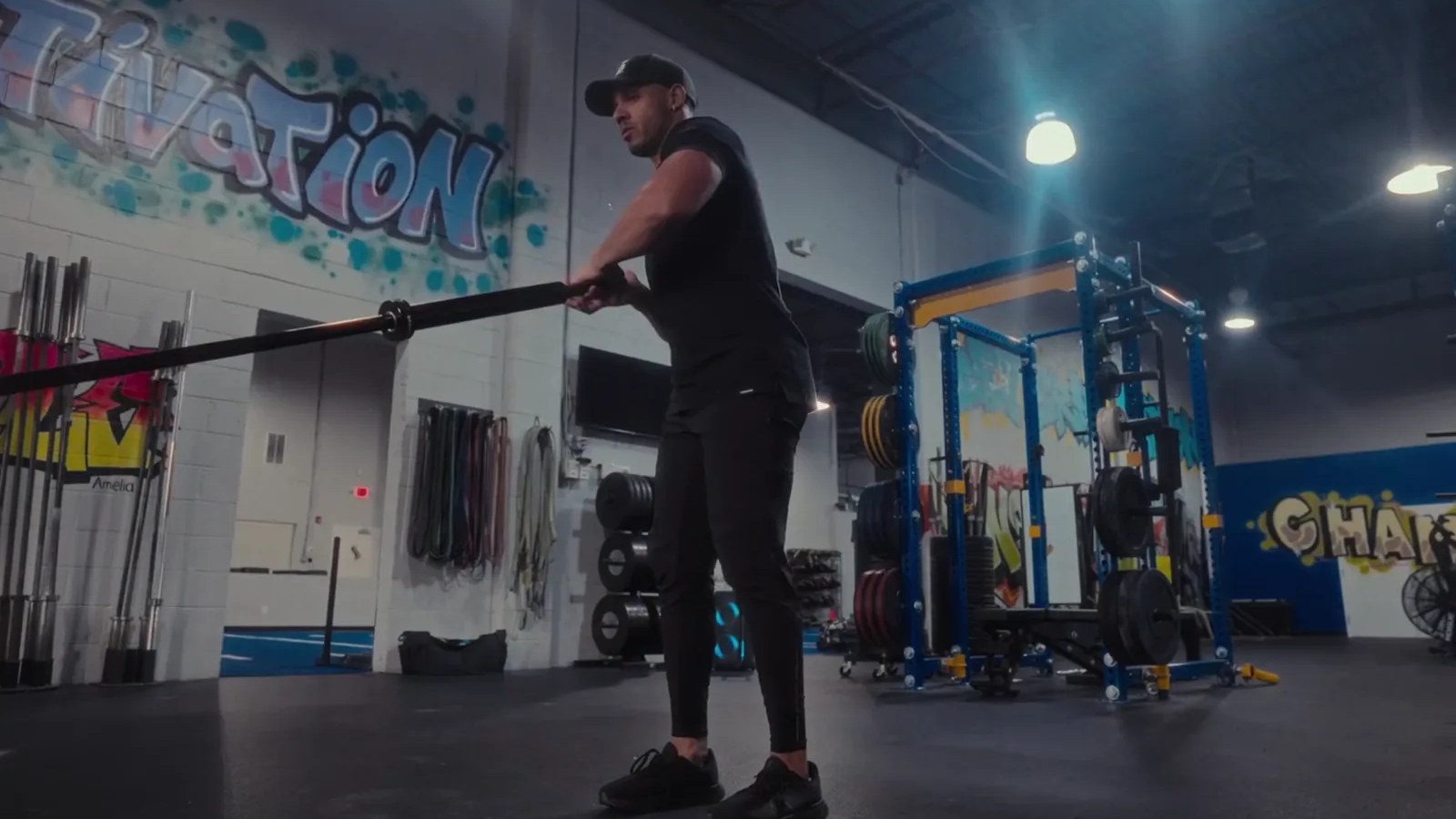 Collis Spann standing with the Spann Bar seated in a landmine at his gym, about to drop into a lunge and press